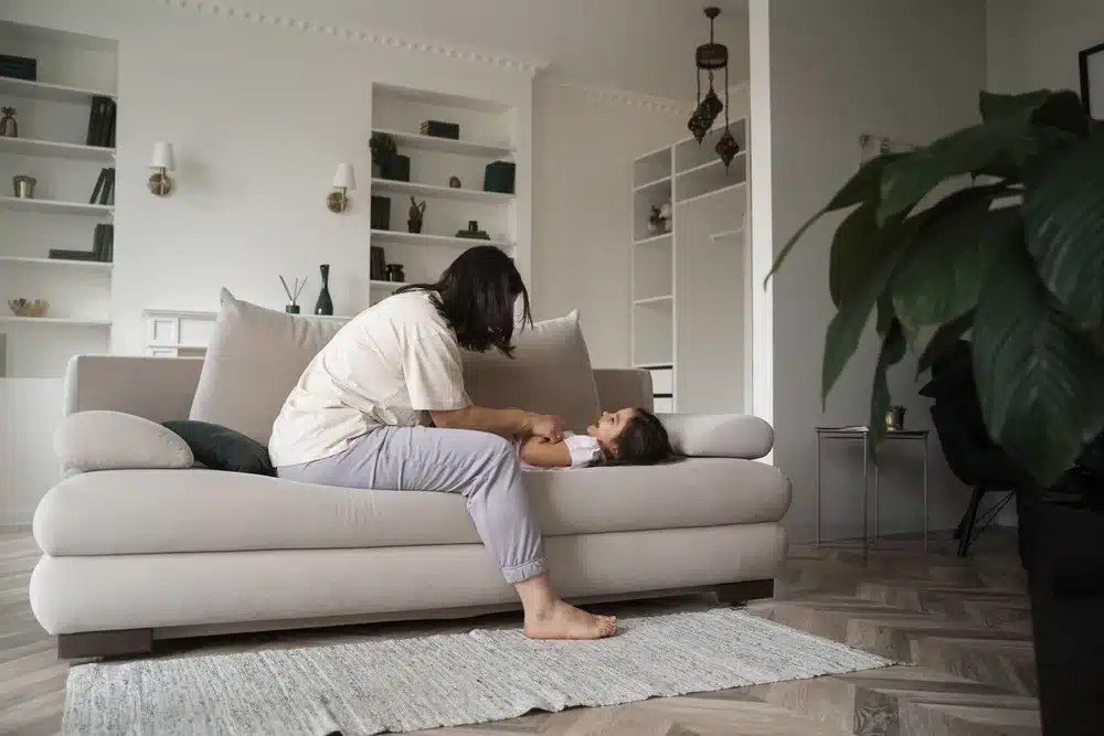 madre haciendo cosquillas niña sofa