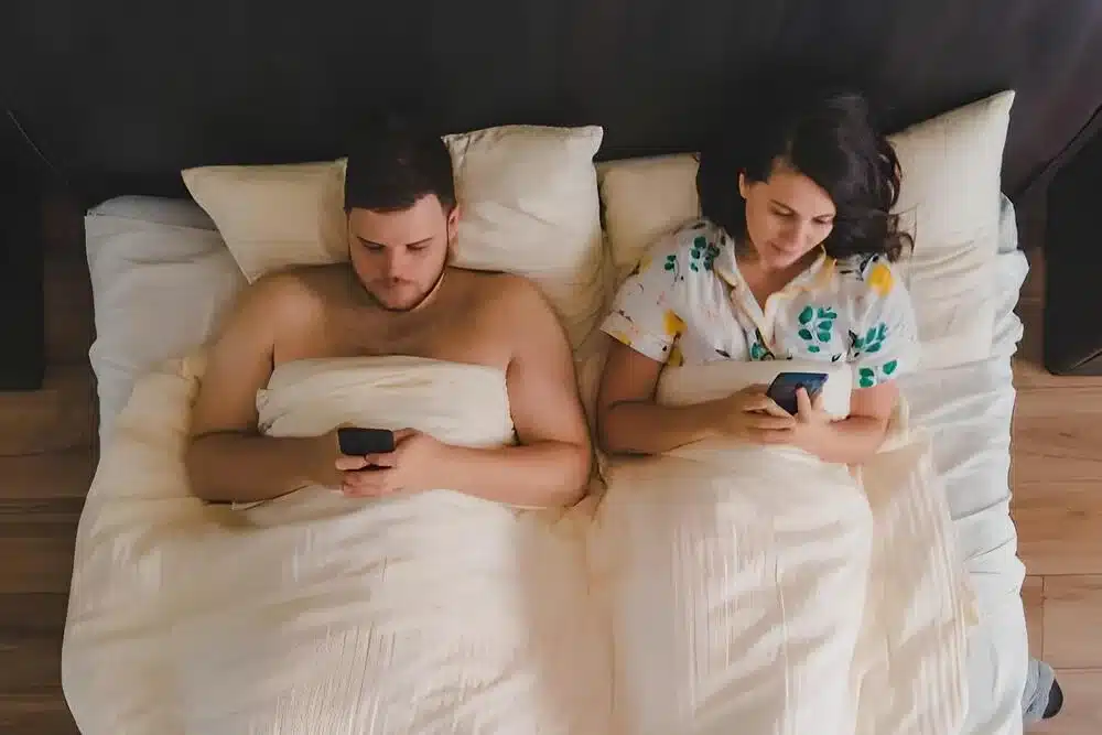 pareja tendido cama navegando internet telefonos